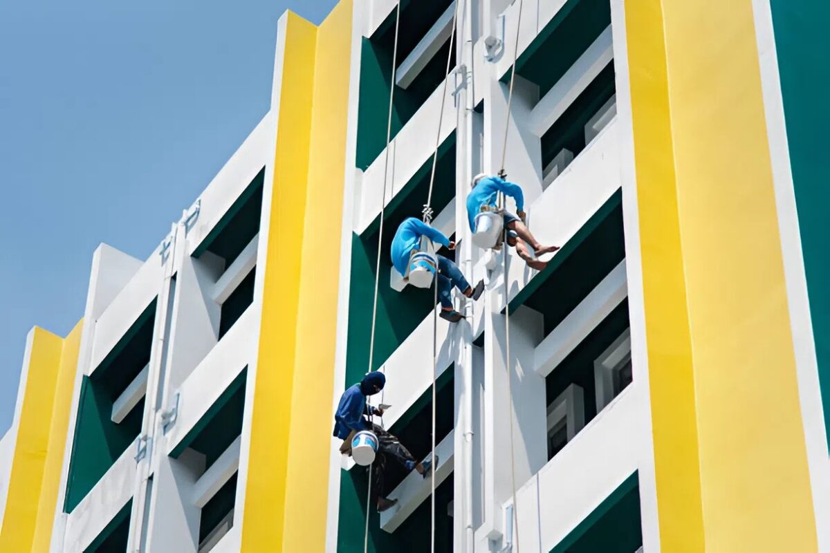 Professional commercial building painters applying durable coatings to a high-rise exterior