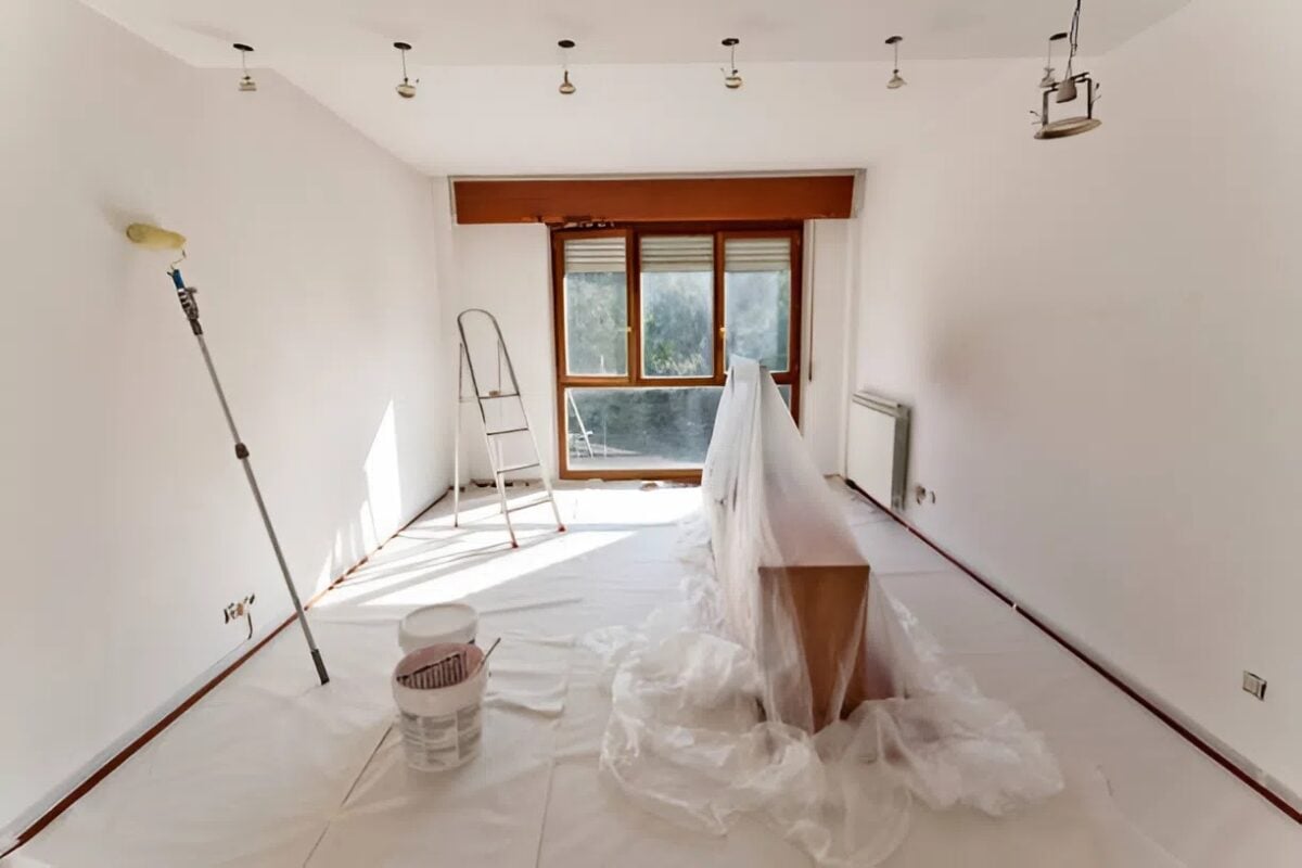 Room prepared for painting with furniture covered in plastic and drop cloths on the floor