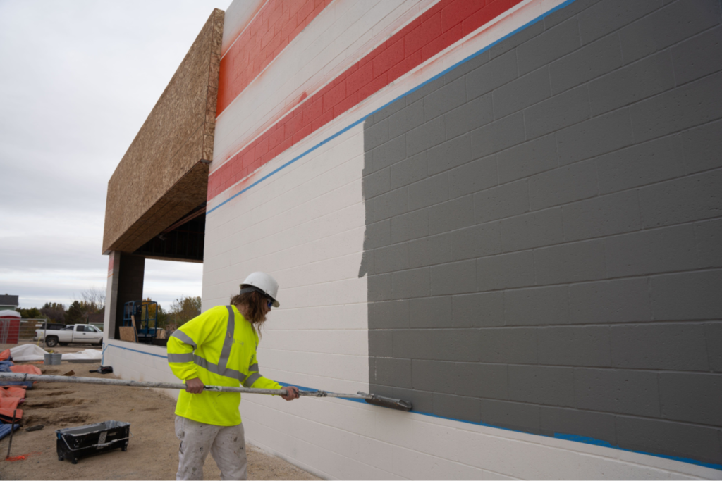 Commercial exterior painting in progress with gray coating applied to a wall by a professional painter in St. Cloud, MN