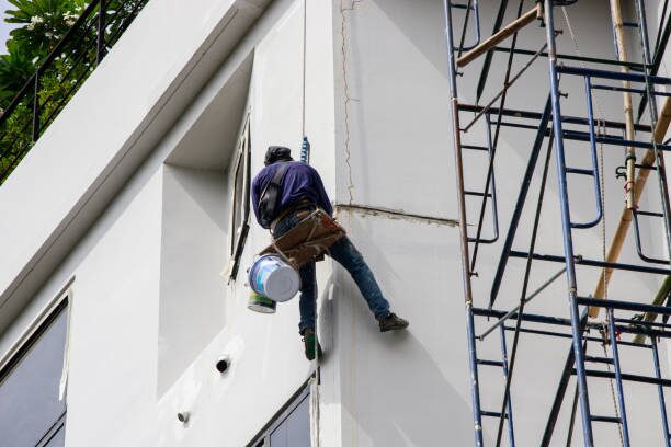 Painter applying exterior paint to a commercial building with durable coatings by a commercial painter in Sauk Rapids, MN.