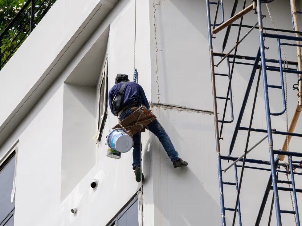 Commercial painter preparing and repainting a modern building exterior by an exterior painter in Elk River, MN